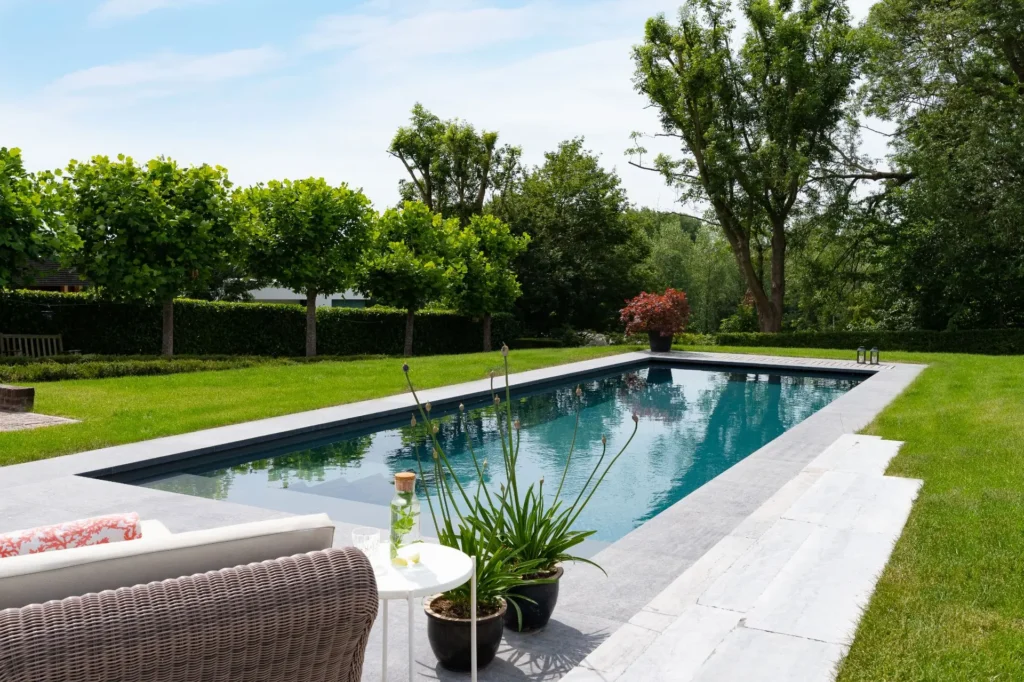 Zwembad met ligstoelen in groene tuin